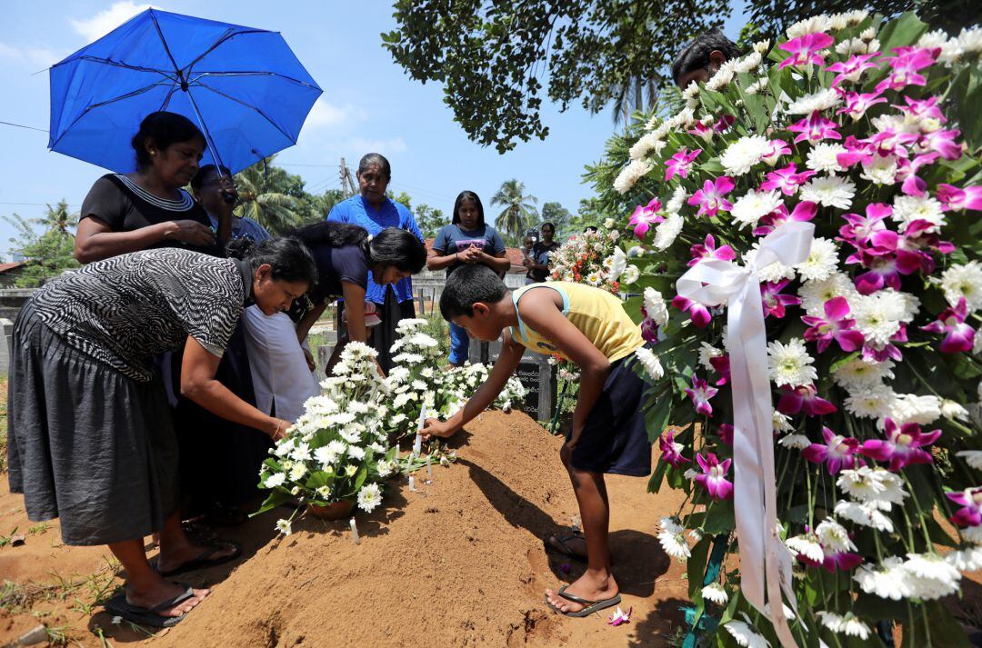 Una familia pone flores en una de las tumbas. 