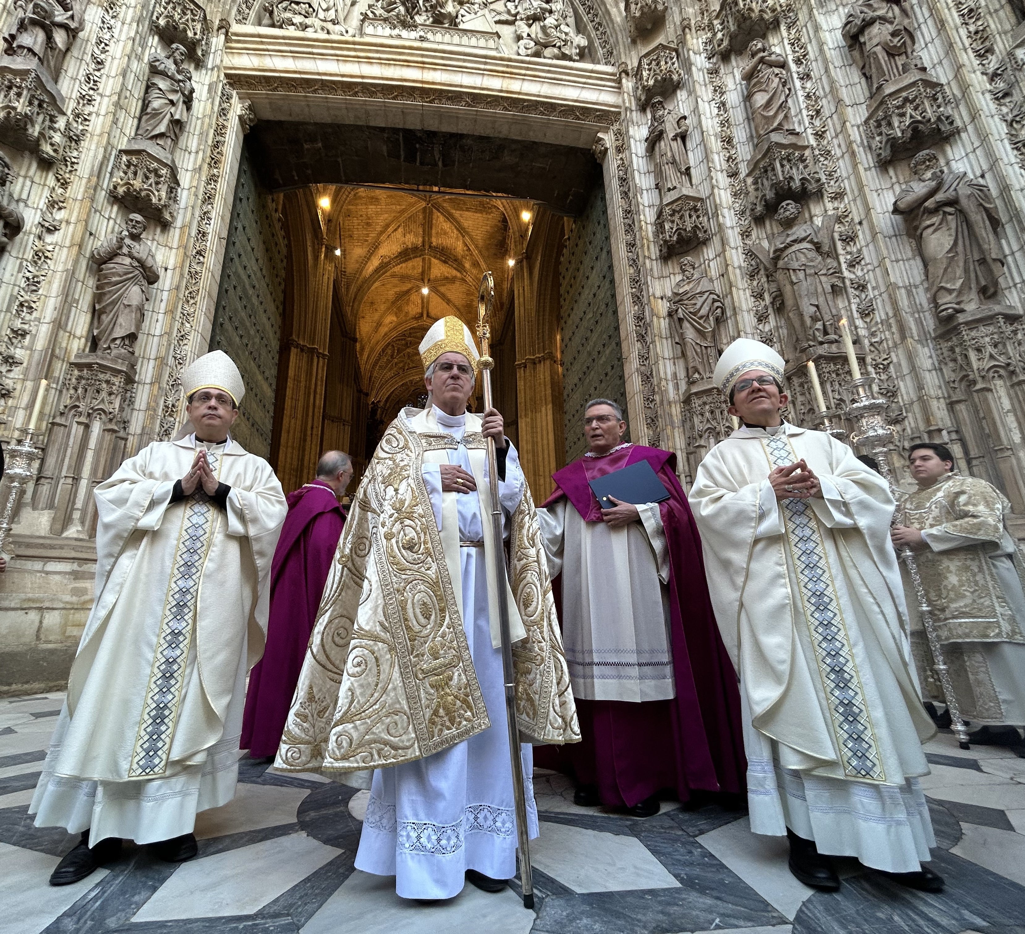 Monseñor José Ángel Saiz Meneses, arzobispo de Sevilla, ante la Puerta de la Asunción de la Catedral junto a sus obispos auxiliares, monseñor Teodoro León (izd) y monseñor Ramón Valdivia (drch)