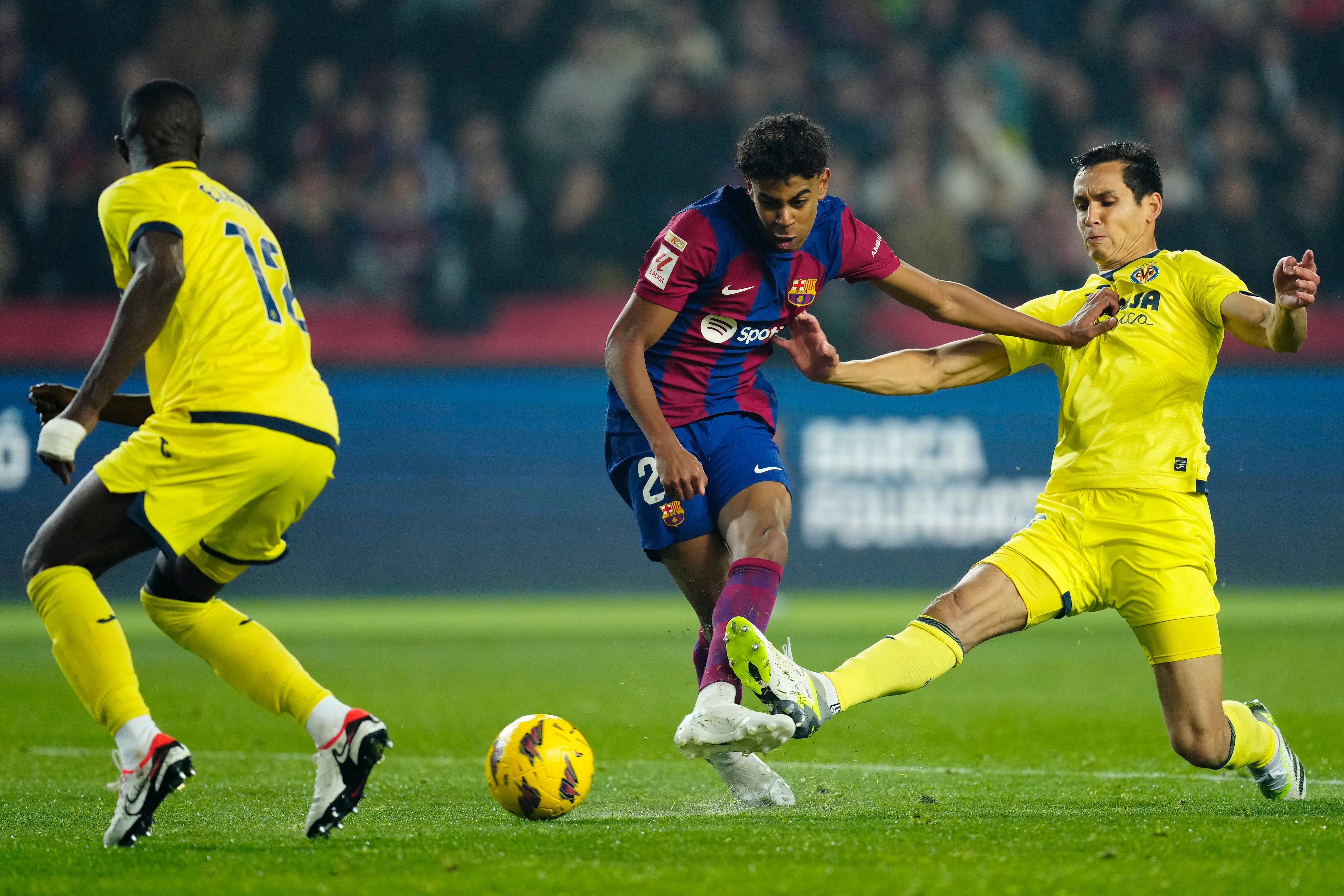 BARCELONA, 27/01/2024.- El delantero del FC Barcelona Lamine Yamal (c) dispara junto a Aissa Mandi (d), del Villarreal, durante el partido de la jornada 22 de LaLiga EA Sports entre el FC Barcelona y el Villarreal CF, este sábado en el estadio Olímpico de Montjuic, en Barcelona. EFE/Enric Fontcuberta
