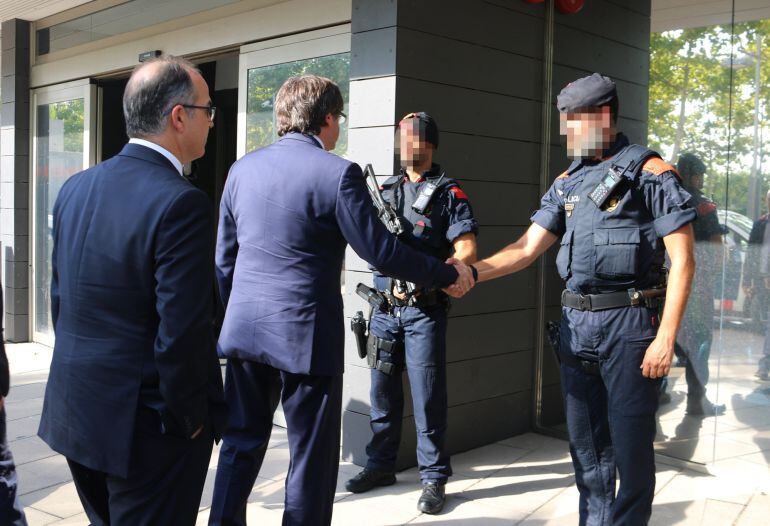 El presidente del Govern, Carles Puigdemont, y el conseller de Presidència, Jordi Turull, saludando a un mosso