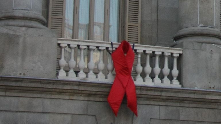 El llaç vermell de la lluita contra la SIDA penja a un balcó de l'Ajuntament de Barcelona 