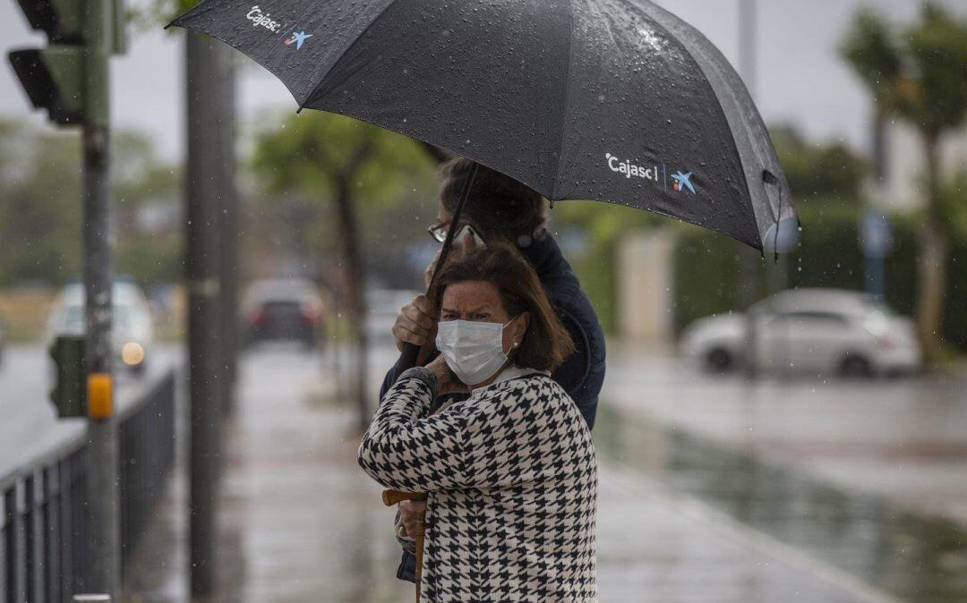 Archivo - Dos personas sujetan un paraguas durante una tormenta.