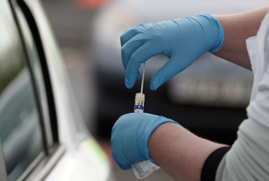Un profesional sanitario recoge una muestra de test de coronavirus realizada a una persona desde un coche.