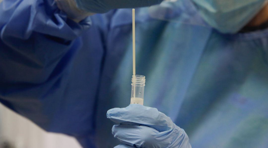 Una trabajadora sanitaria sostiene una probeta con una prueba PCR