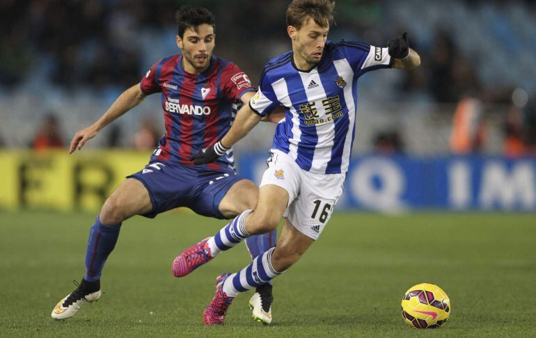 El centrocampista de la Real Sociedad Sergio Canales disputa un balón con el defensa del Eibar Eneko Bóveda.