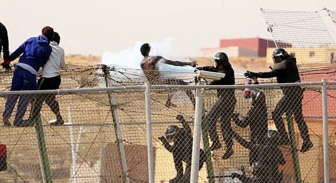 Miembros de los Grupos de Reserva y Seguridad (GRS) de la Guardia Civil rocían con un extintor a uno de los inmigrantes en la valla de Melilla.