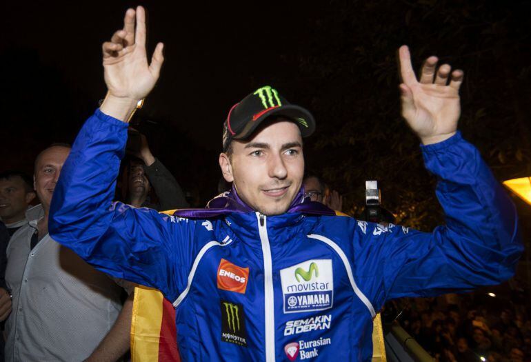GRA519. PALMA DE MALLORCA, 12/11/2015.- El piloto Jorge Lorenzo saluda desde el autobus descapotable en el que ha recorrido las calles de Palma de Mallorca, a los aficionados que han asistido esta noche a la celebración del campeonato del mundo de Moto GP, conseguido el pasado Domingo en el circuito de Cheste. EFE / Cati Cladera.