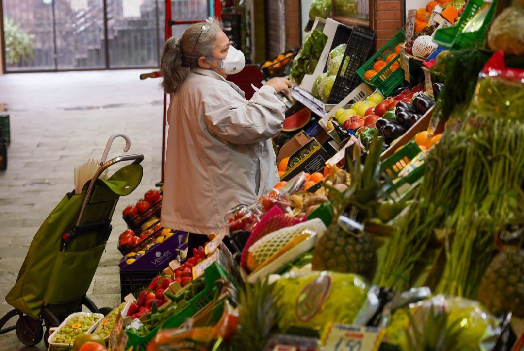 Una señora con mascarilla comprando en el mercado de Triana