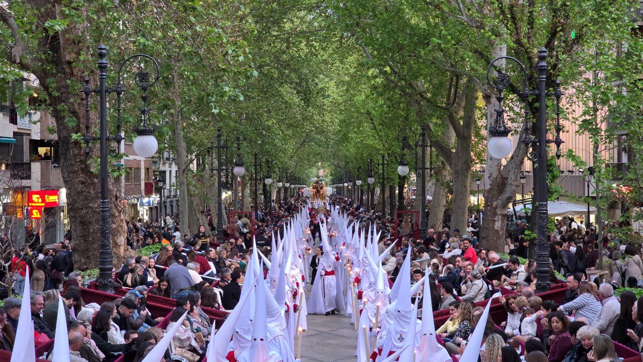 Los nazarenos de la hermandad de La Aurora desplegados delante del paso de Jesús del Perdón por la Carrera de la Virgen, primeros metros de la ampliada carrera oficial en el Jueves Santo de Granada de 2025