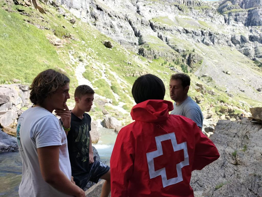 Imagen de un voluntario de Cruz Roja junto a visitantes de Ordesa y Monte Perdido