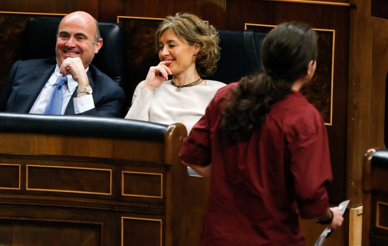 El líder de Podemos, Pablo Iglesias (d), pasa junto a los ministros en funciones de Economía, Luis de Guindos (i), y de Agricultura, Isabel García Tejerina (c), después de su intervención en la sesión plenaria