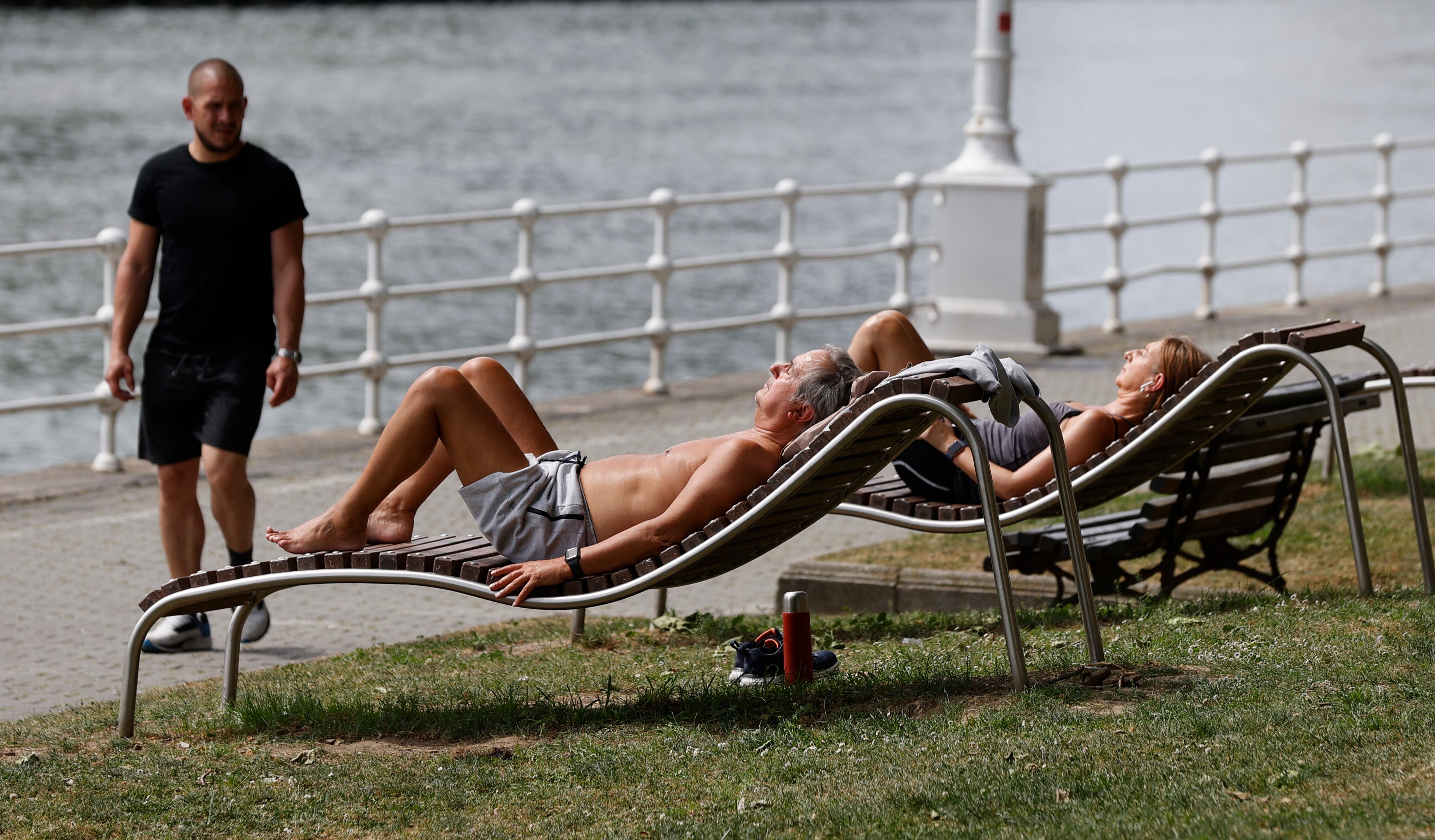 Dos personas toman el sol junto a la ría de Bilbao, como consecuencia de las altas temperatura que se registran. EFE/Luis Tejido