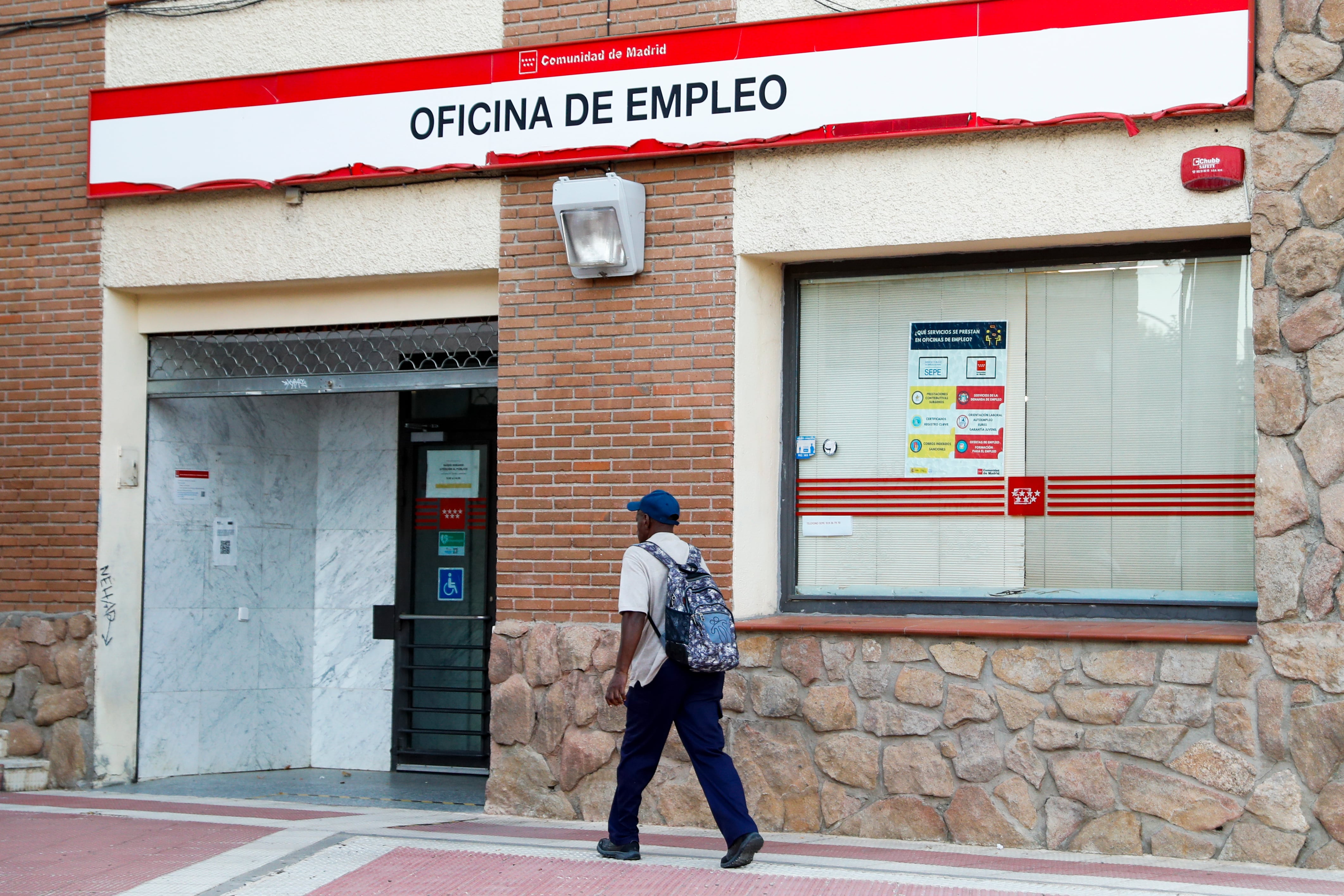 Un hombre camina junto a una oficina de empleo