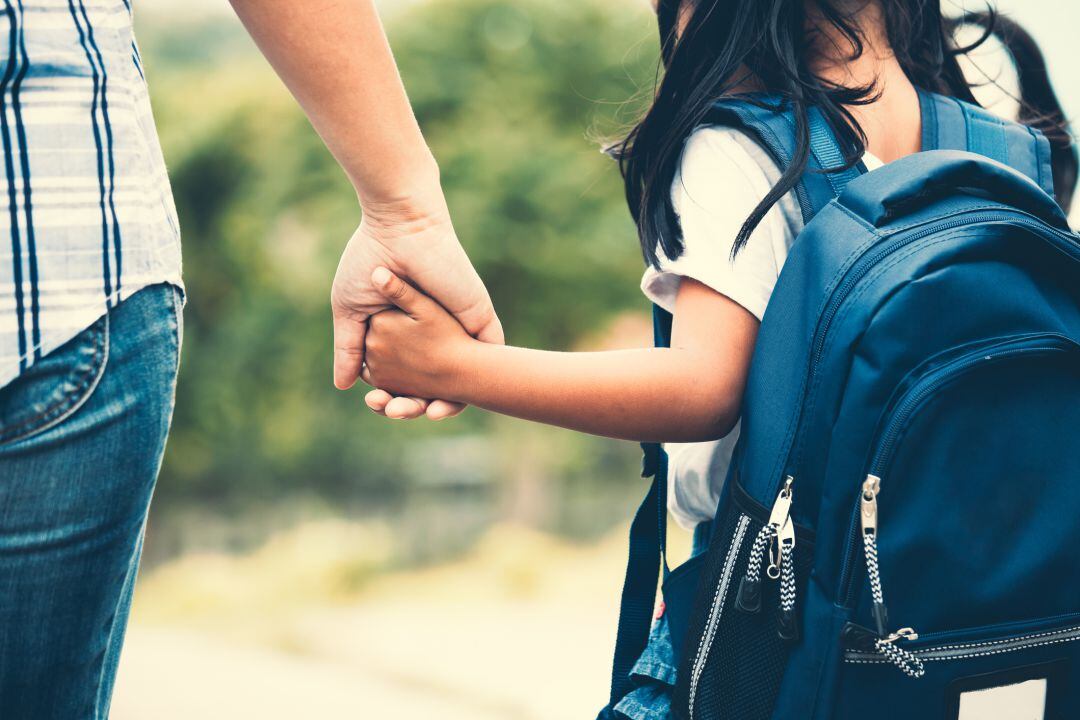 Niña va al colegio de la mano de su madre