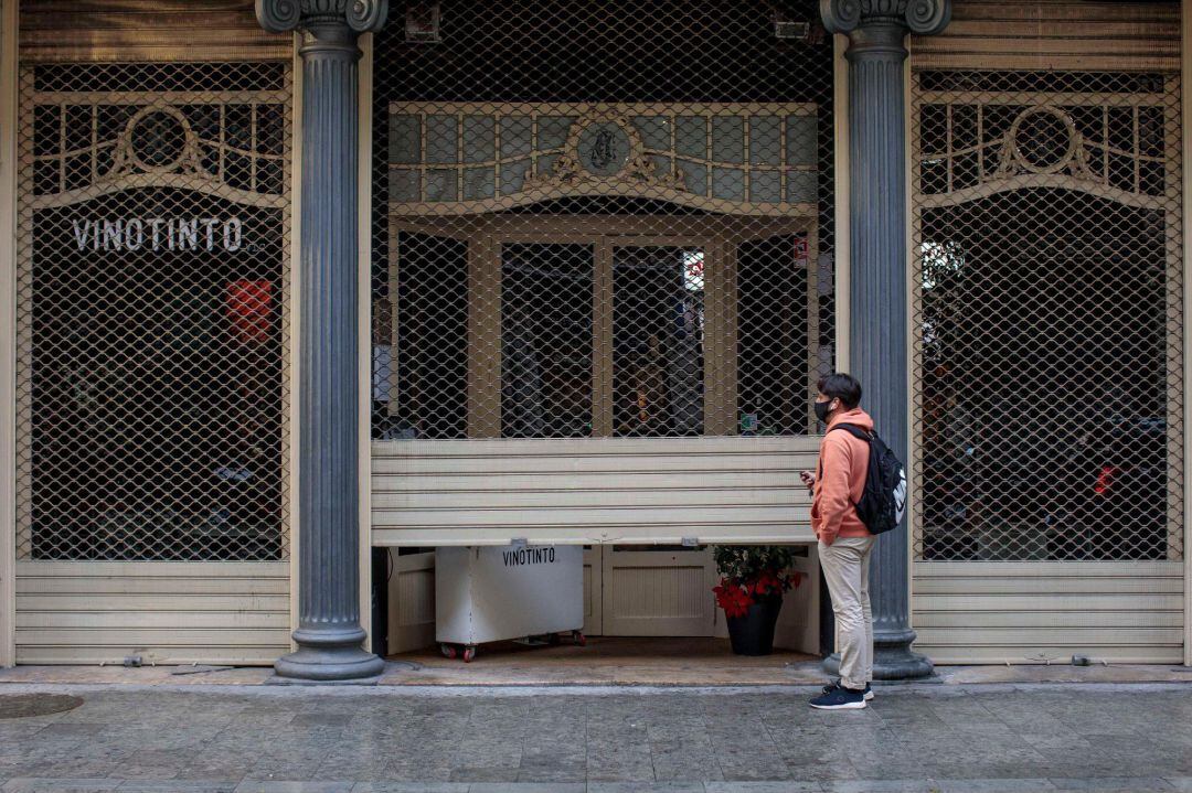 Un trabajador de un restaurante del centro de València cierra el local el día que se aplica en la Comunitat Valenciana las nuevas medidas contra la pandemia de coronavirus