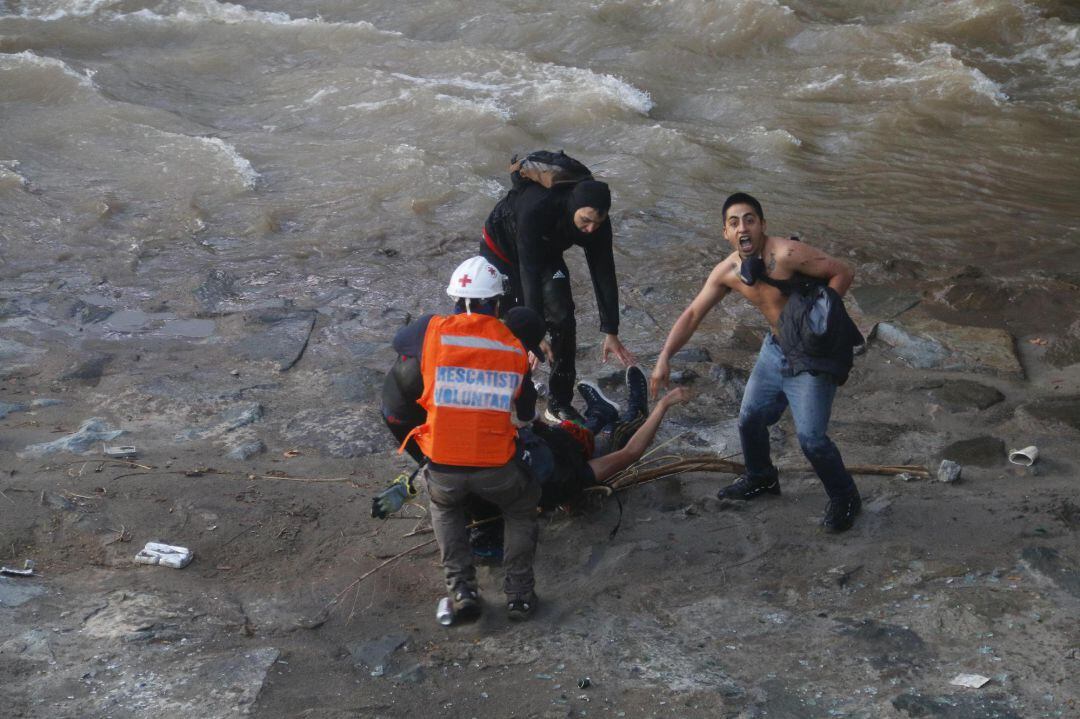 Manifestantes y equipos de emergencia socorren a una persona que se encuentra inconsciente luego de caer en el río Mapocho durante protestas en contra del gobierno de Sebastián Piñera