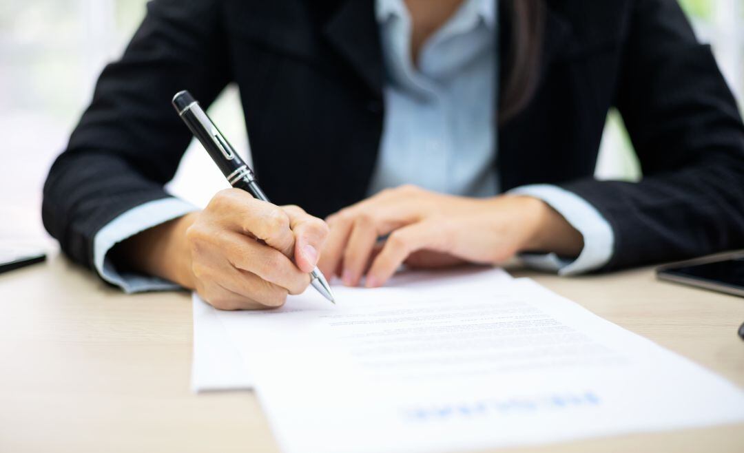 Una persona firma unos documentos.