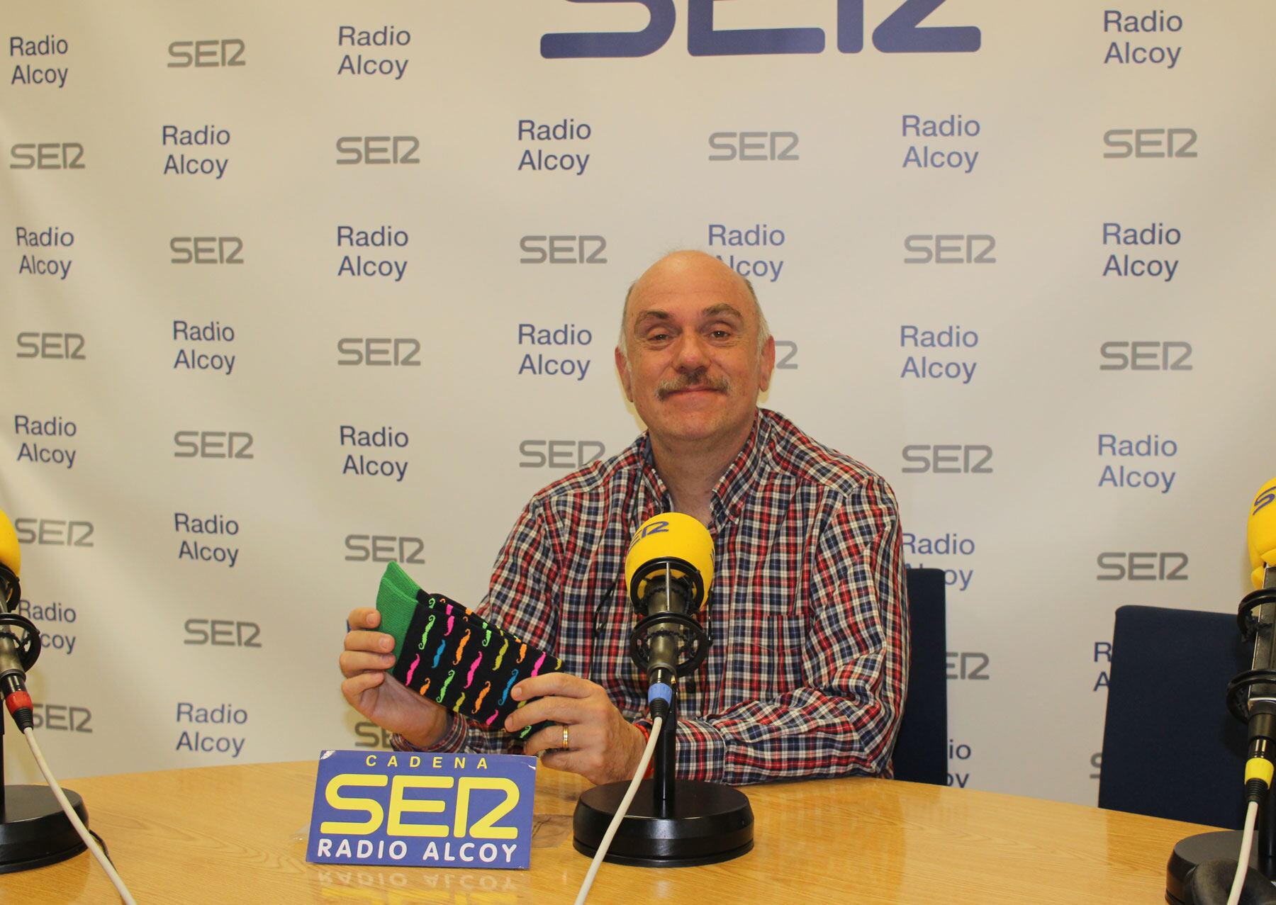 Gabi Barrachina, en el estudio central de Radio Alcoy, muestra uno de los pares de calcetines que están a la venta por un motivo solidario