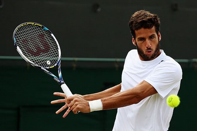 Feliciano López devuelve una bola durante su partido ante Isner en Wimbledon