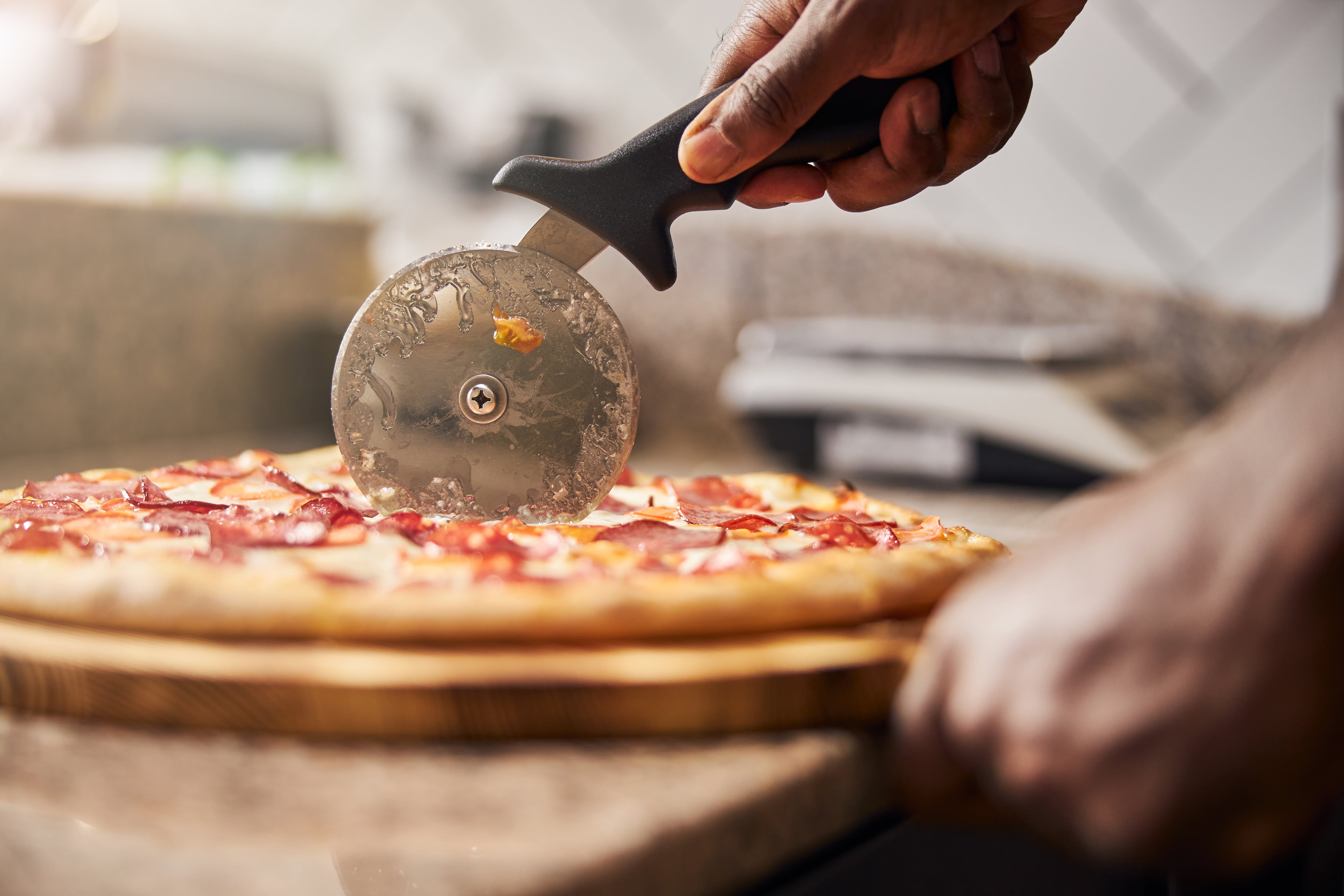 Una persona corta una pizza con la rueda.