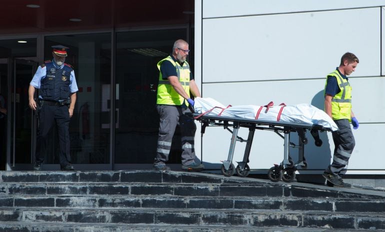 Miembros del servicio judicial retiran el cadáver del hombre que ha sido abatido esta mañana al intentar acceder a la comisaría de los Mossos de Cornellà con un cuchillo en la mano y al grito de &quot;Alá es grande&quot;