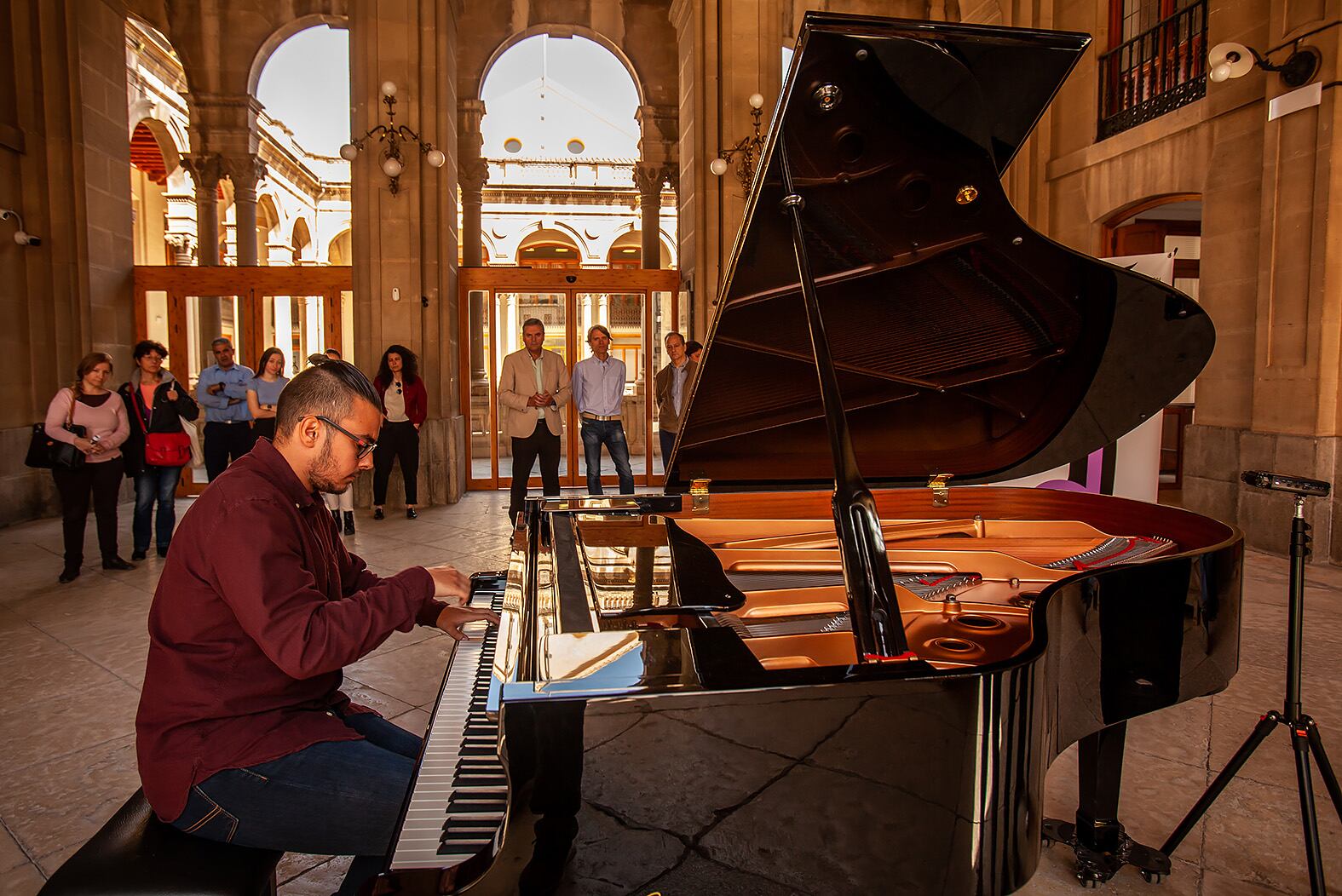 Un joven estudiante toca el piano en la entrada de la Diputación Provincial de Jaén.