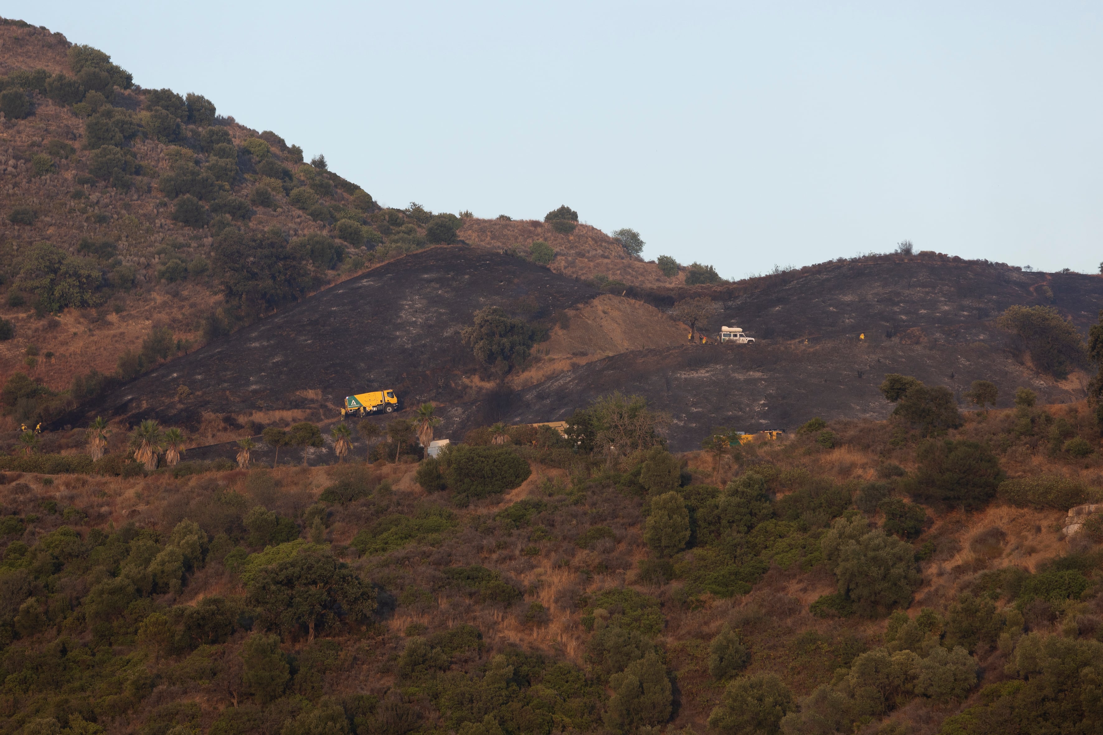 Miembros del Infoca trabajan en el incendio forestal declarado este lunes en el paraje de Nagüeles, en Marbella (Málaga), que llegó a movilizar 14 medios aéreos entre aviones y helicópteros. EFE/ Carlos Díaz