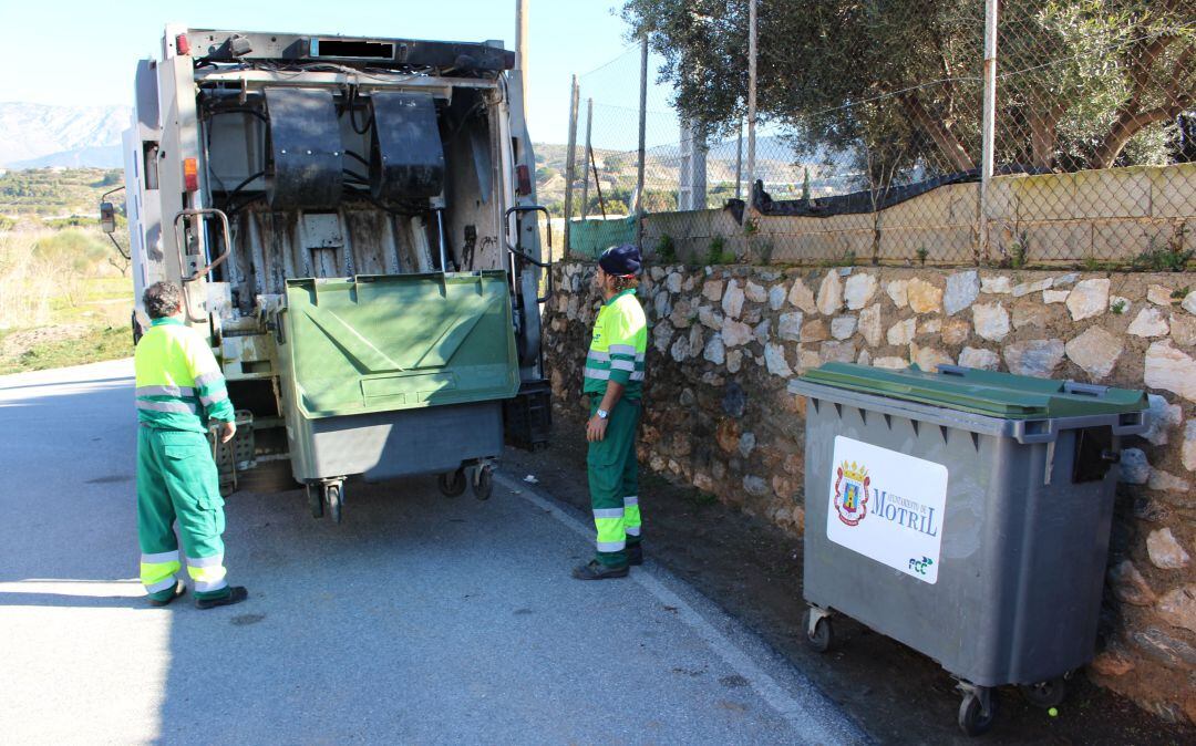 Operarios de limpiezan depositan la basura del contenedor al camión