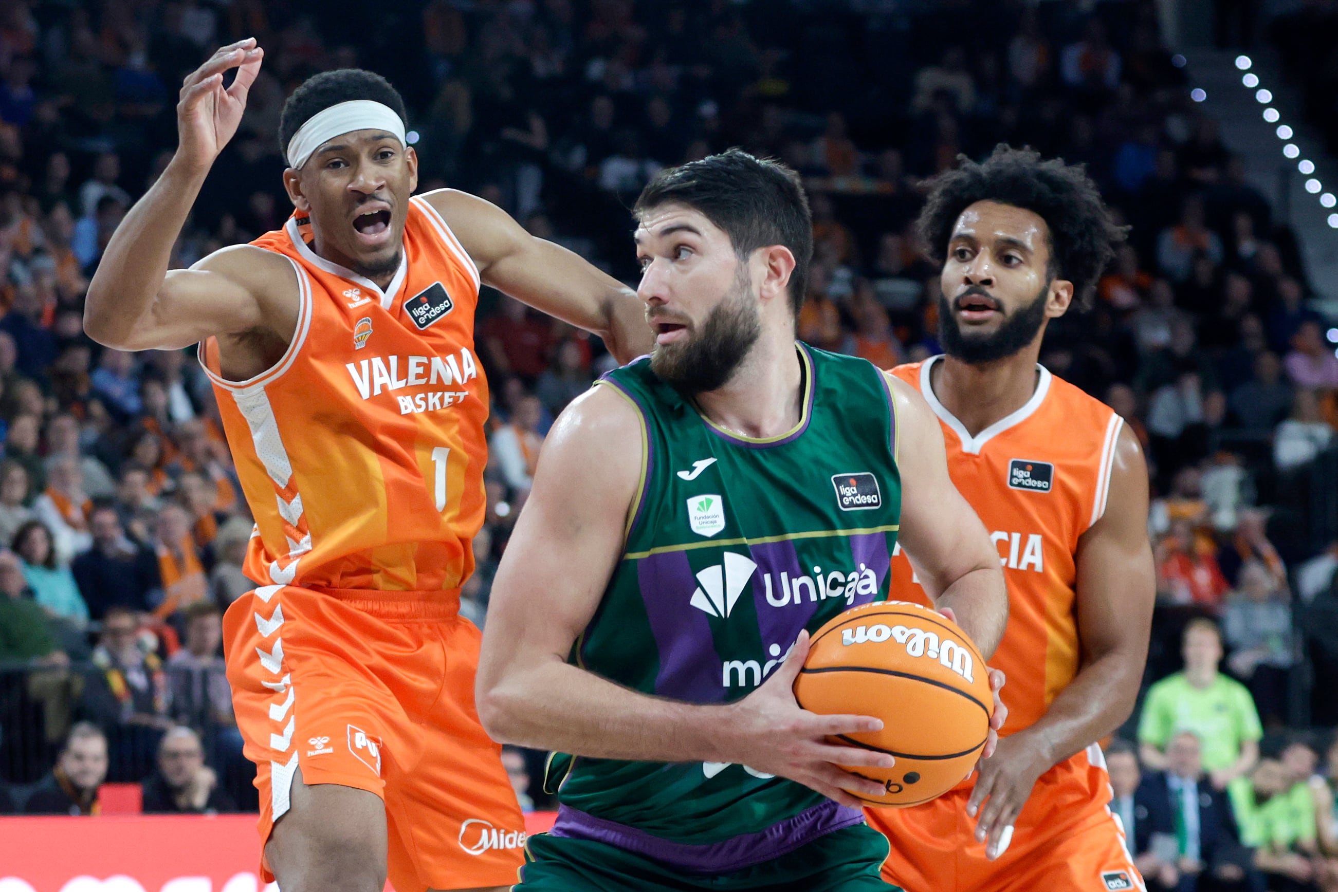 VALENCIA, 10/01/2026. El alero francés del Unicaja Killian Tillie (c) en acción ante Kameron Taylor (i) del Valencia Basket durante el encuentro correspondiente a la fase regular de la Liga Endesa que disputan hoy sábado Valencia Basket y Unicaja en el pabellón Roig Arena de Valencia. EFE/Miguel Ángel Polo.