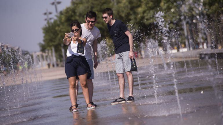Un grupo de turistas se refresca del intenso calor en una de las fuentes del centro de Córdoba. 