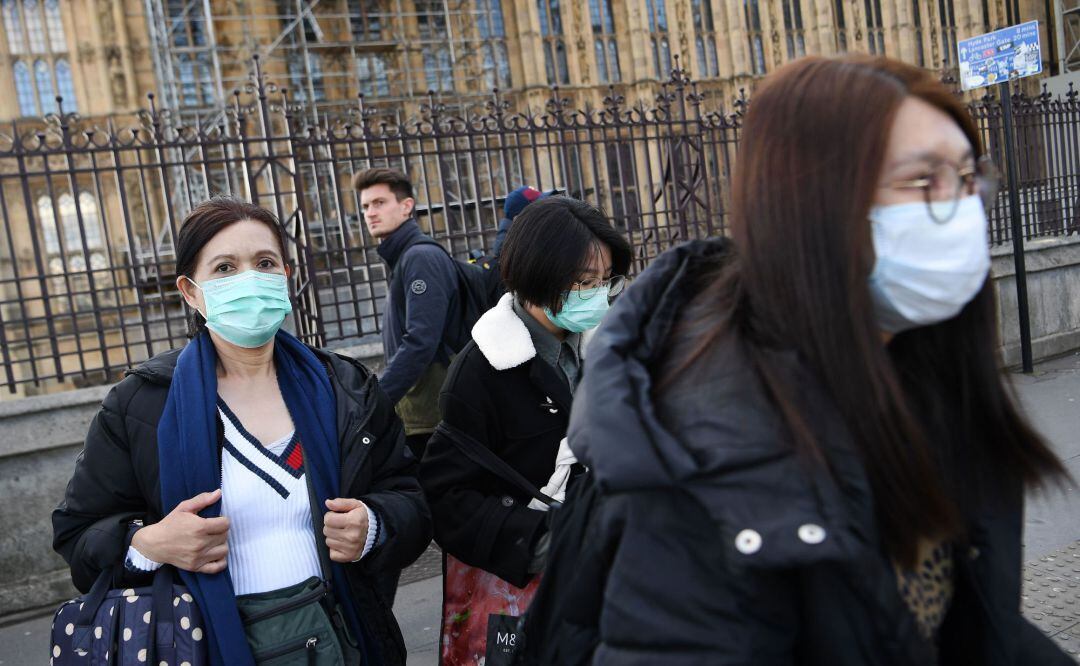 Turistas pasean con mascarillas cerca del parlamento británico en Londres