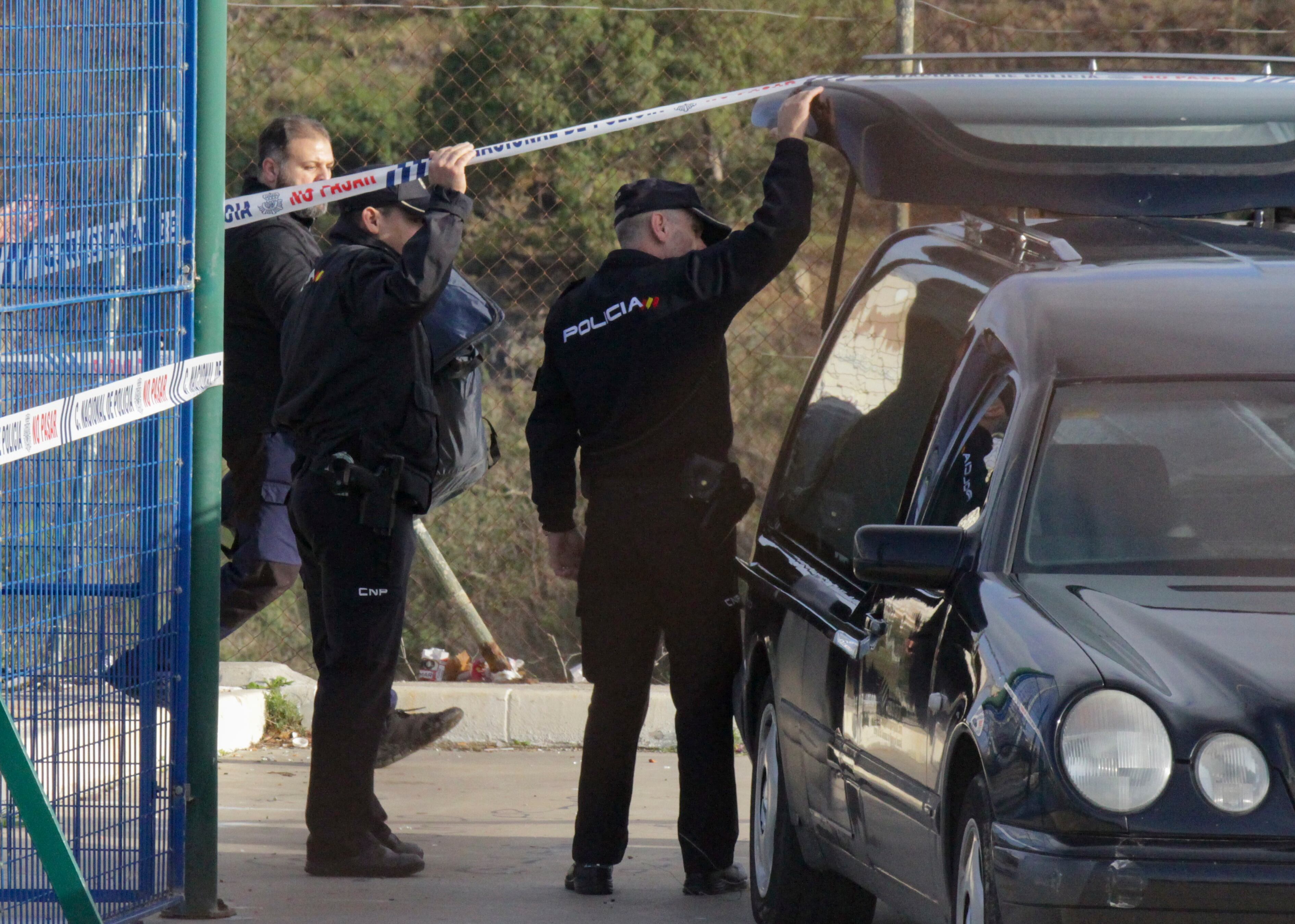 Agentes de la policía junto al coche fúnebre.