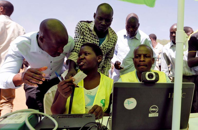 Funcionarios de la Comisión Electoral Independiente y Limites (IEBC) ayudan a los residentes a confirmar sus datos para inscribirse para votar en las elecciones generales de 2017 en los barrios bajos de Kibera, en Nairobi