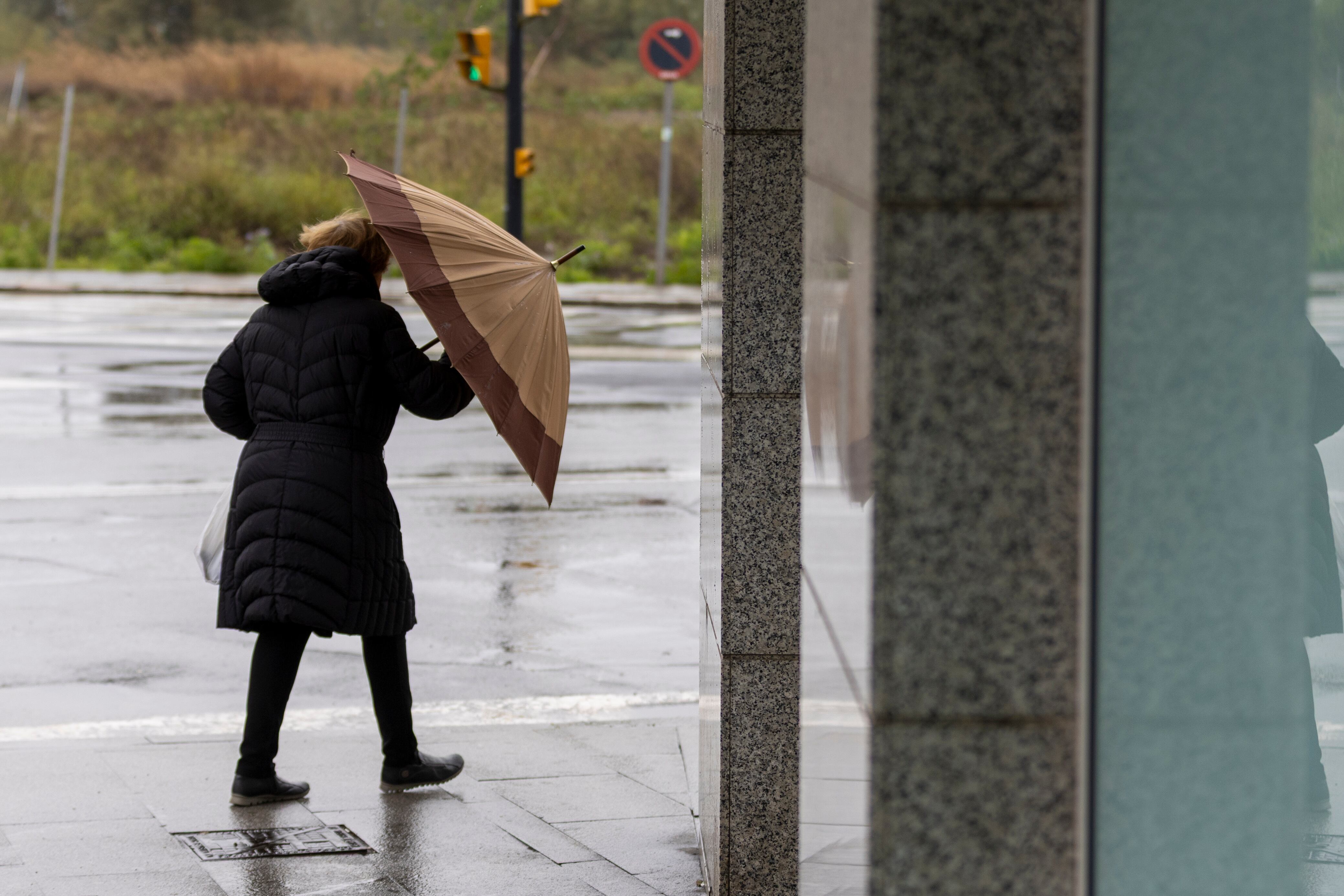 Una mujer se protege del viento y la lluvia este sábado en Huelva