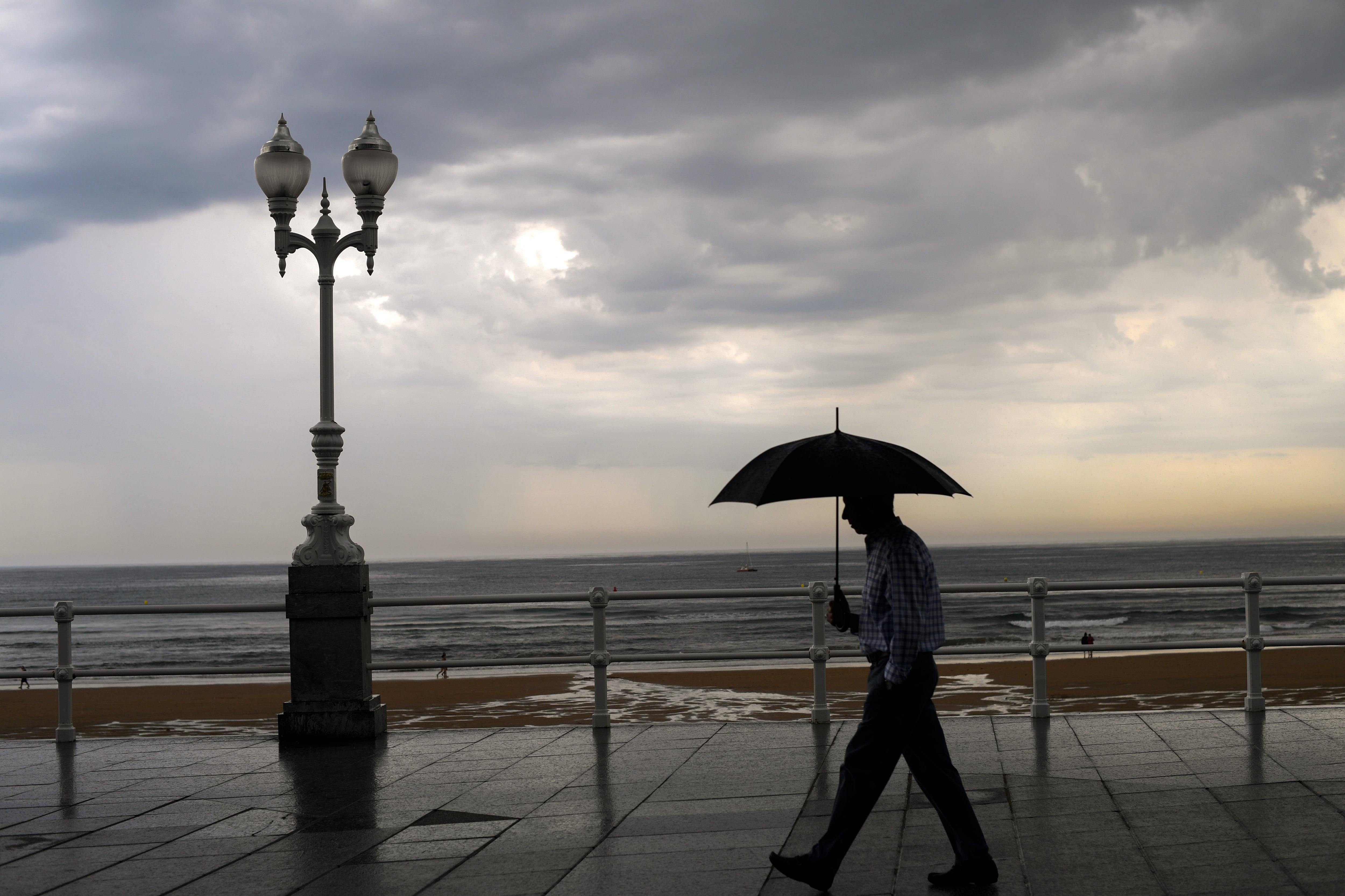 Un hombre se protege con el paraguas de la lluvia