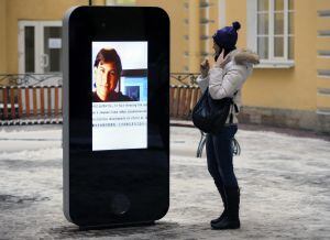 FILE- In this file photo dated Thursday, Jan. 10, 2013, a woman stands next to a screen showing a portrait of Steve Jobs on the recently erected memorial to late Apple Corp. co-founder in the courtyard of the Techno Park of the St. Petersburg National Res