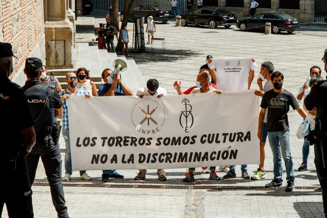 Agentes de la Policía Nacional vigilan a las casi 20 personas del sector taurino que han protagonizado una protesta a las puertas del Ayuntamiento de Toledo a la llegada de la ministra de Trabajo, Yolanda Díaz