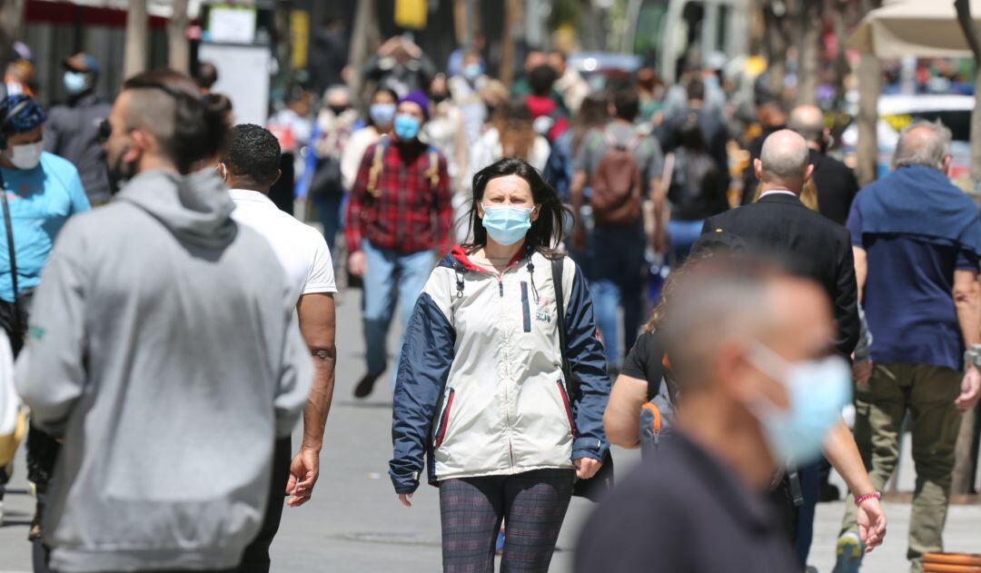 Varias personas caminan con mascarilla.