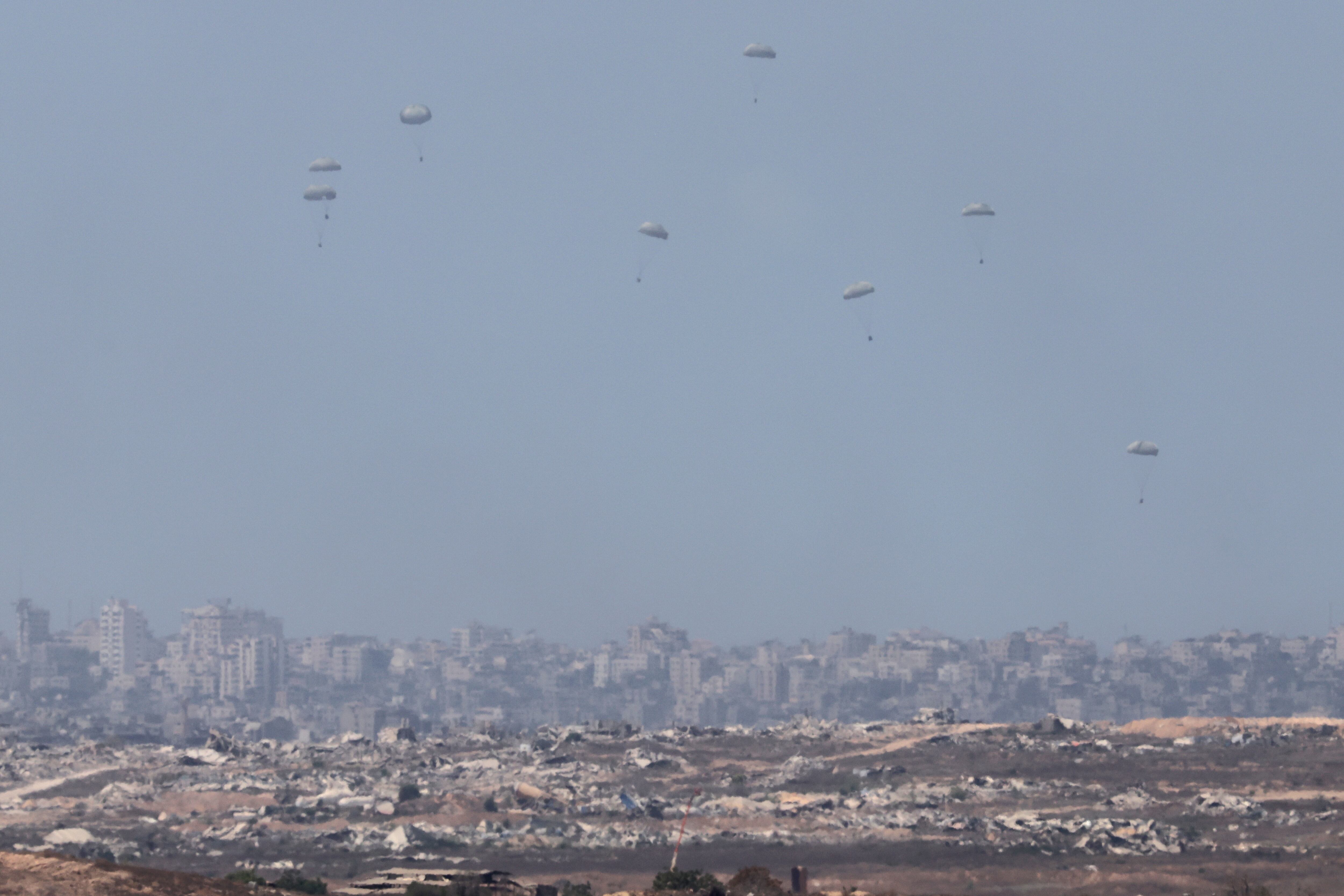 La ayuda humanitaria es lanzada desde un avión militar sobre la parte norte de la Franja de Gaza, tal y como se ve desde el lado israelí de la frontera con Gaza, en el sur de Israel.