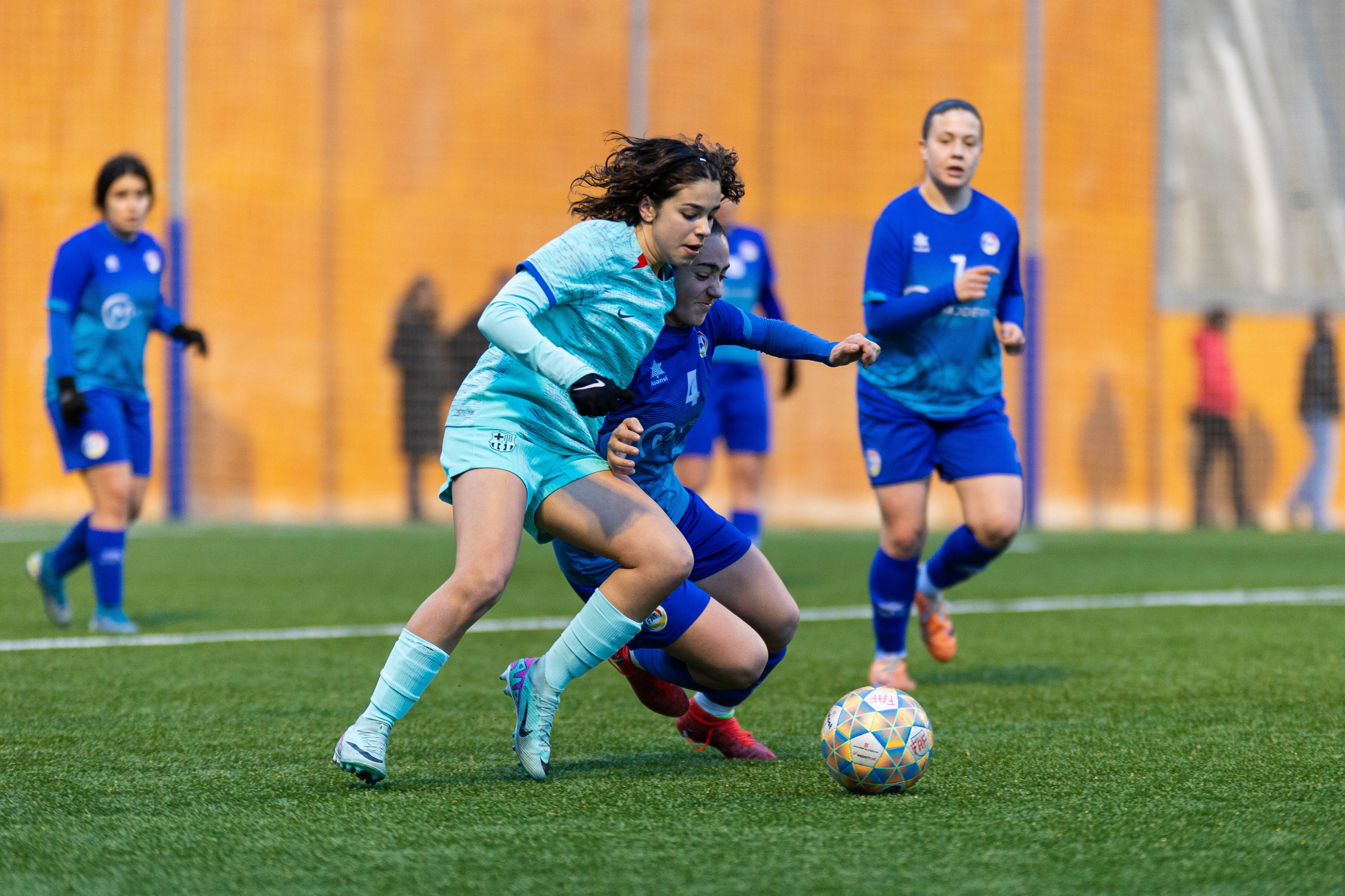 Una jugadorra del FC Barcelona C disputa una pilota amb una defensa de l'Enfaf femení al partit disputat dissabte al camp Francesc Vila de la Massana.