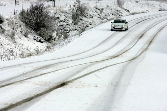 Un vehículo circula por una de las carreteras del puerto de San Isidro, en León, durante la nevada registrada en la región.