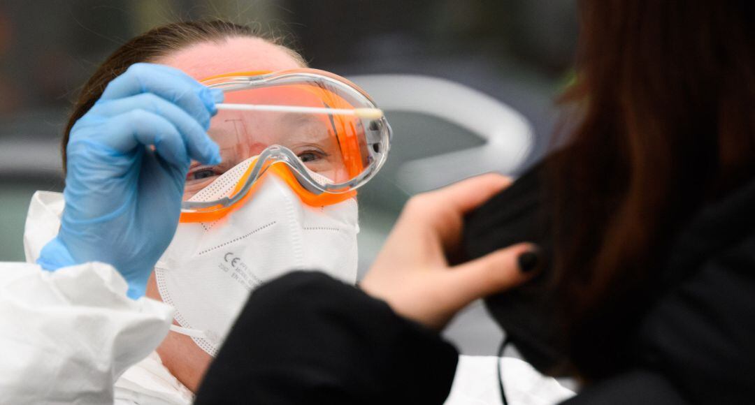 Una enfermera realiza una PCR a una mujer.