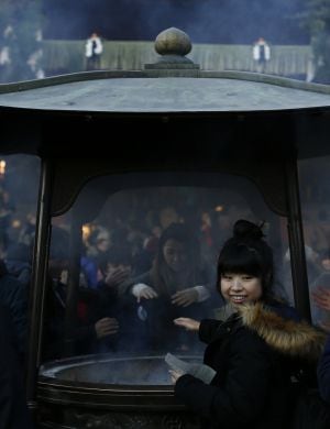 Una mujer japonesa intenta purificarse con el humo del incienso.