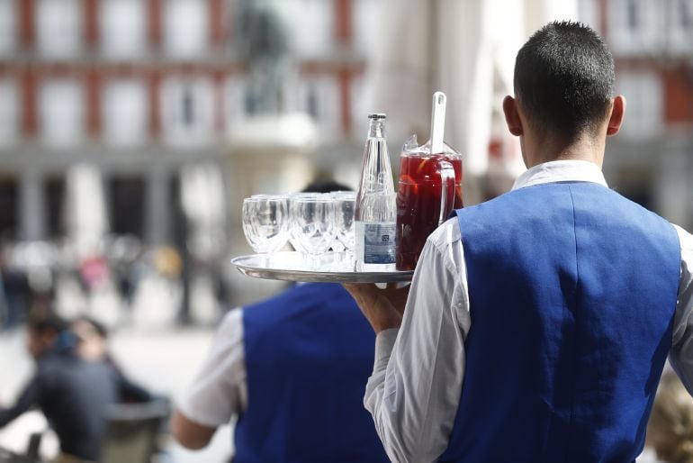 Un trabajador del sector de la hostelería surbiendo copas en una terraza