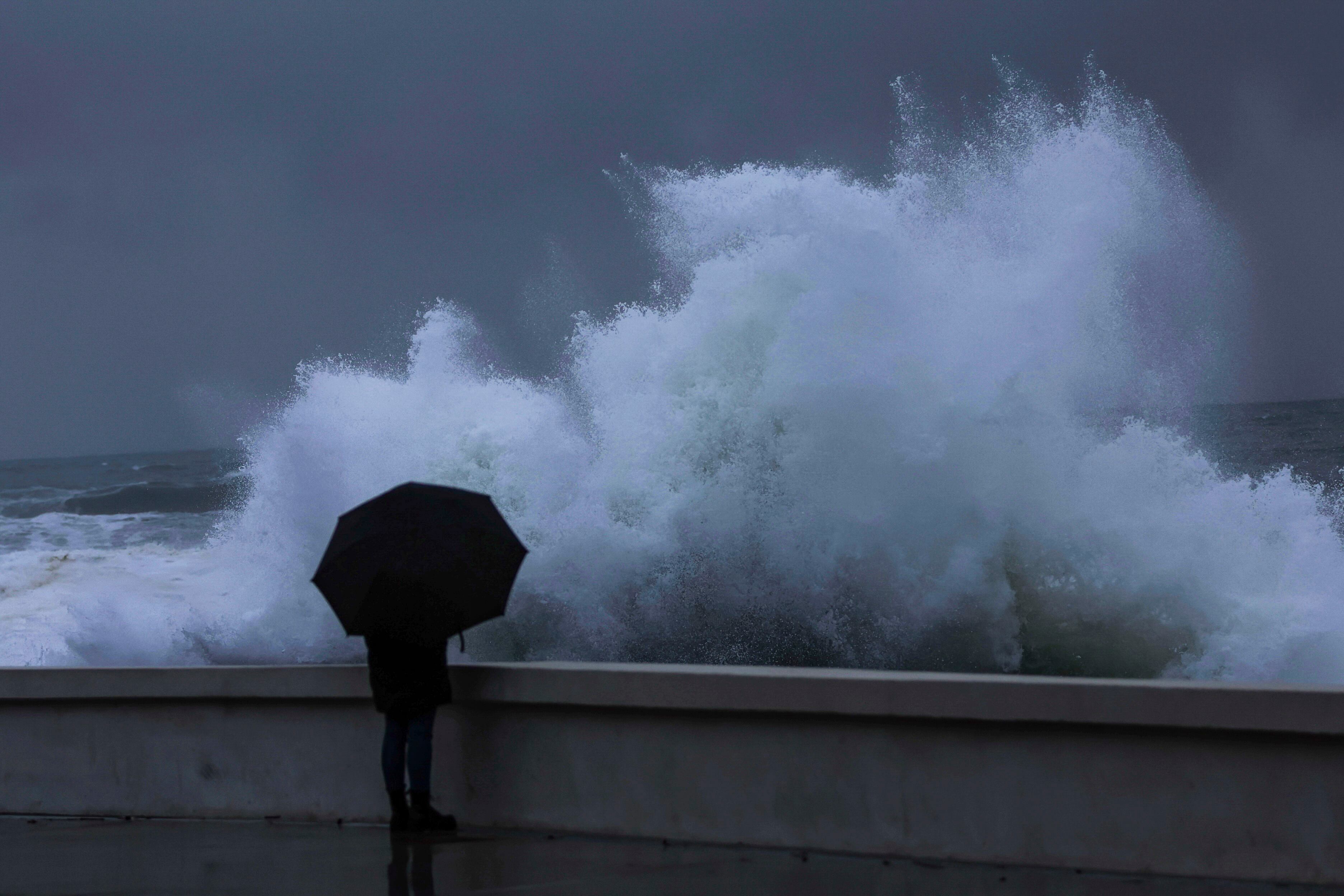 Una persona observa como rompe el fuerte oleaje de este viernes en la costa de Baiona (Pontevedra)