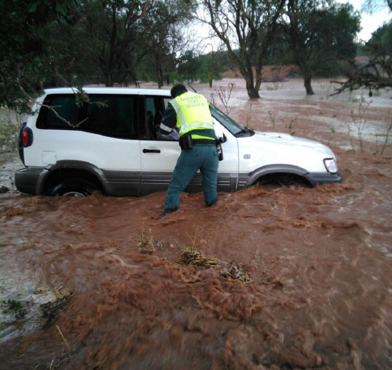 Los efectivos del destacamento de tráfico de Sarrión rescatando a los 3 ocupantes de un vehículo que se han visto sorprendido por la crecida de un barranco en la A-232 en Valbona. 