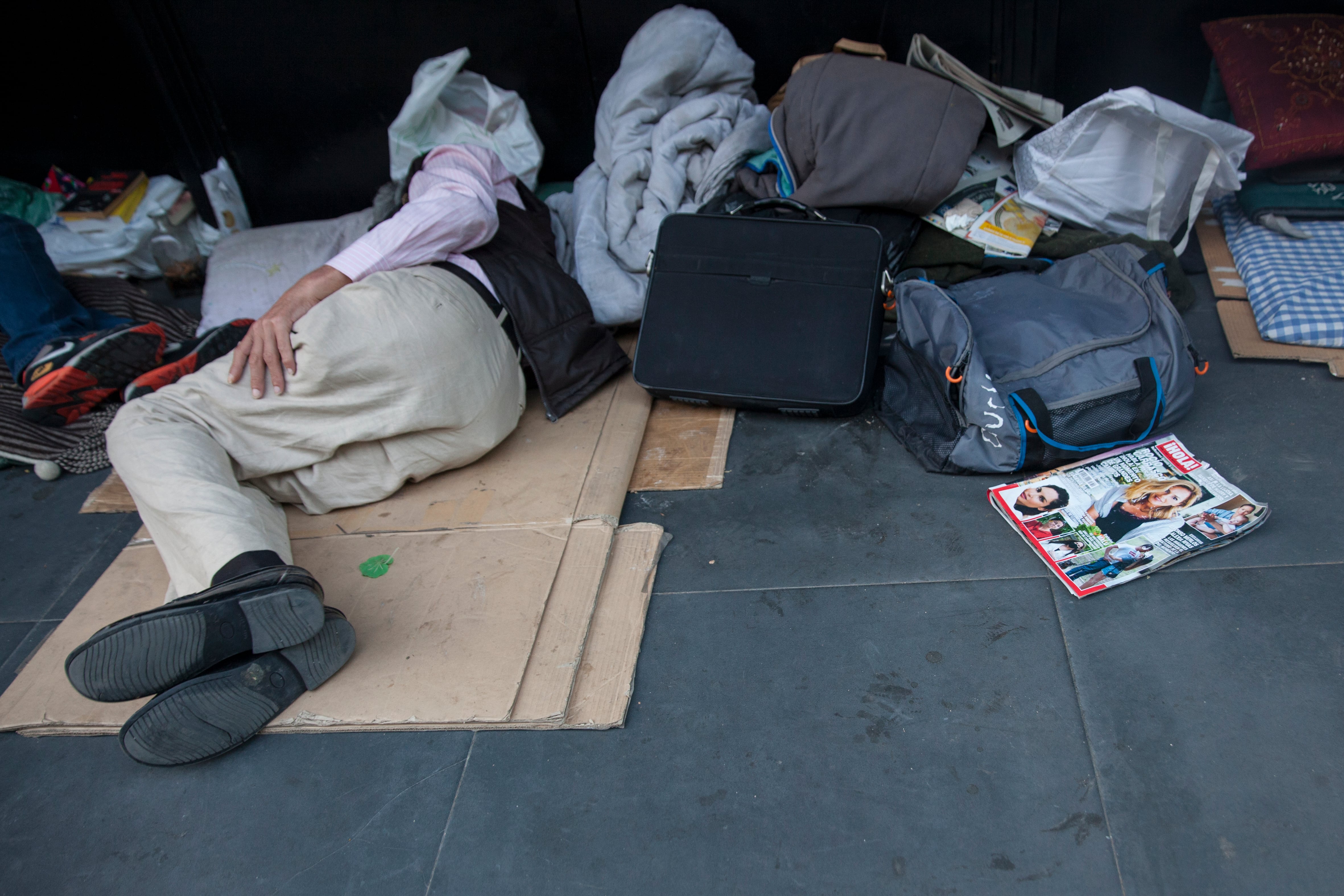 Un hombre tumbado sobre unos cartones una calle del madrileño Barrio de Salamanca