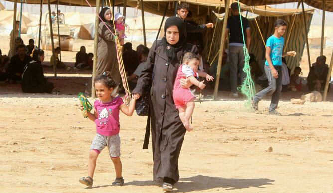 Una mujer refugiada siria y sus dos hijos en el campamento de refugiados de al Zaatri, cerca de la frontera de Siria con Jordania