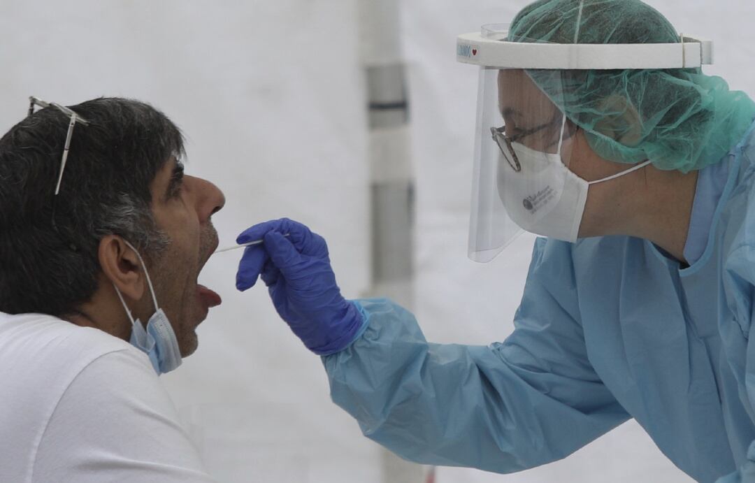 Una sanitaria le realiza un frotis bucal a un paciente.