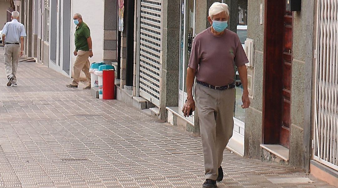 Un hombre camina con mascarilla.